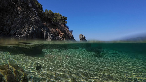 Over-under prizor Egejskog mora sa bistrom vodom ispod površine i pogledom na stene iznad